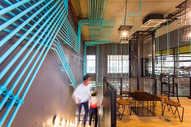จากโถงอาคารแบบ double height ceiling ขึ้นสู่ชั้น 2 โดดเด่นสะดุดตาด้วยการเรียงร้อยท่อสายไฟเหล็กสีฟ้าเลื้อยไปเป็นแนวยาวไปรอบๆ พื้นที่ของผนังและเพดาน
