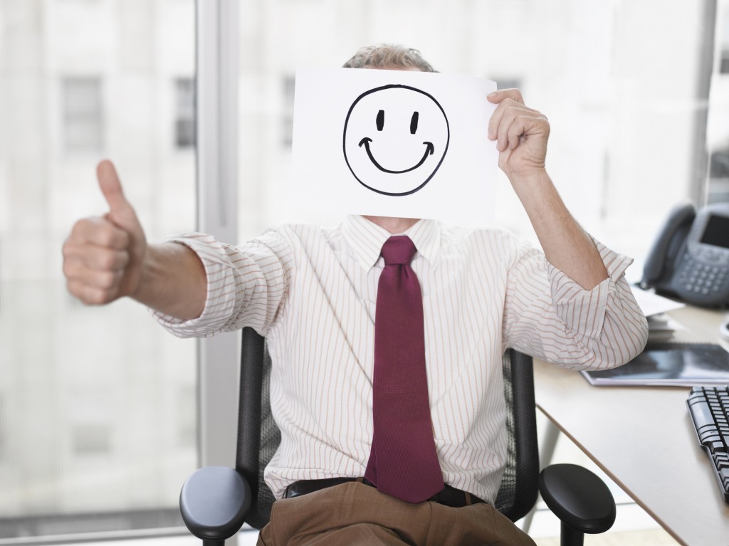 Businessman holding picture of happy face