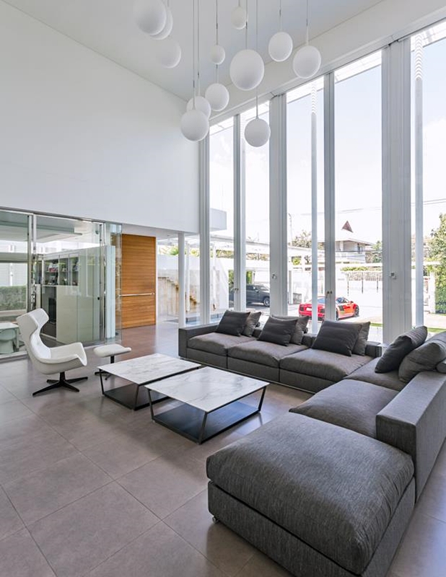 ลักษณะการจัดวางเฟอร์นิเจอร์ภายในห้องนั่งเล่นซึ่งเป็นพื้นที่โล่งแบบ Double Height Ceiling คำนึงถึงความลงตัว สวยงาม และเกิดประโยชน์ใช้สอยสูงสุดไปพร้อมกัน โดยการจัดวาง Sofa Bed ที่มีพนักต่ำตัวใหญ่เพื่อแบ่งอาณาเขตได้พอดีและไม่บดบังทัศนียภาพเมื่อมองเข้ามาจากหน้าบ้าน