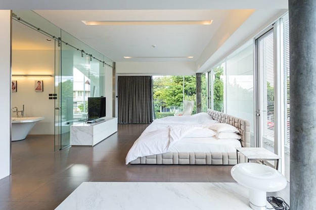 ห้องนอน Master Bedroom จัดวางเตียงนอนจาก Mobilia ขนาบเลานจ์แชร์ Poltrona Frau Regina II สีขาว และโต๊ะข้างท็อปหินอ่อน Vito Small Table จากแบรนด์ FlexForm