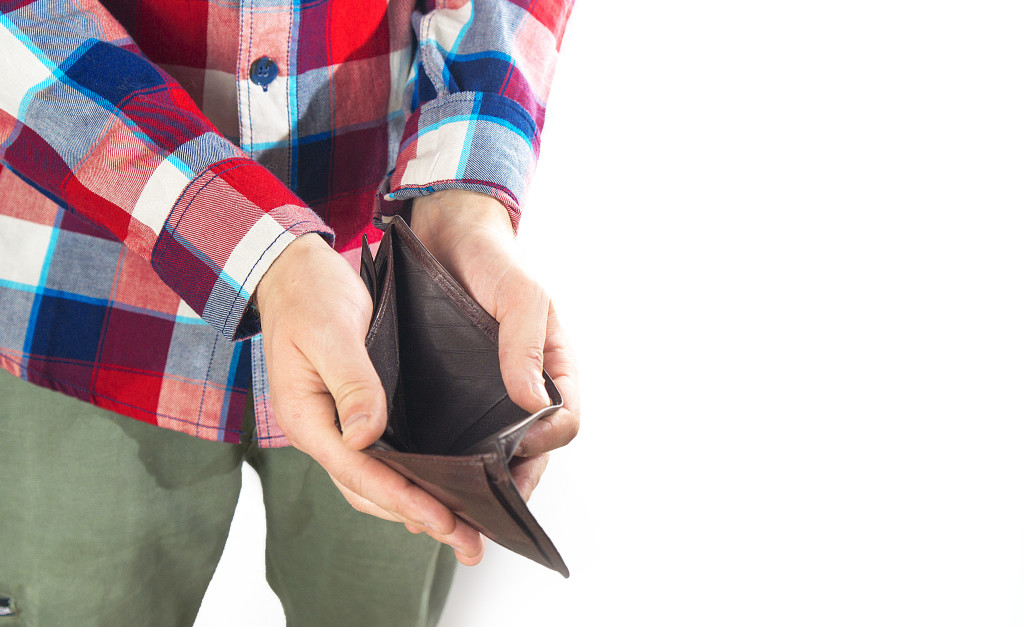 Man with an empty wallet on a white background, not enough money