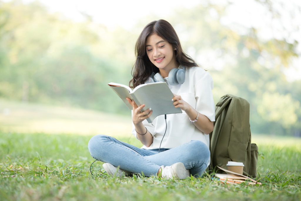 Asian Woman reading book with attractive smiling at garden. Peop