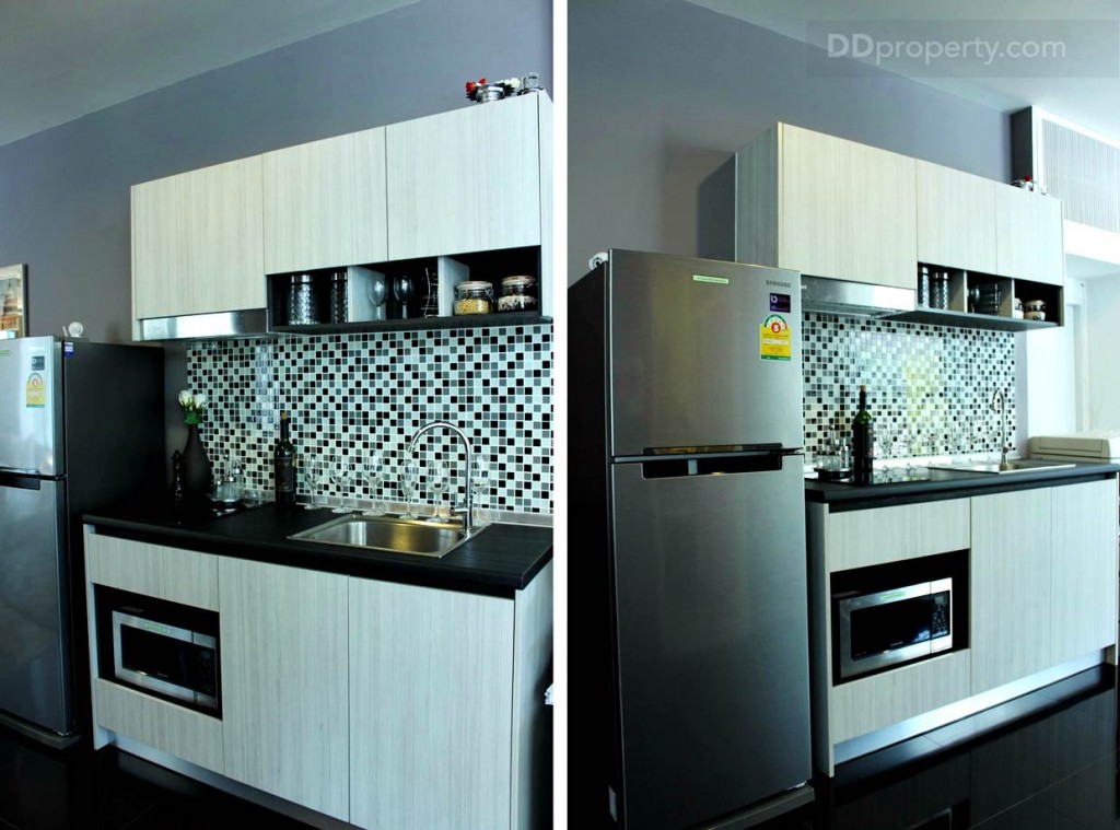 ชุดครัวเป็นแบบบิลท์อินติดกำแพง ประตูตู้และชั้นวางของเป็นพื้นฟิวลามิเนตลายไม้