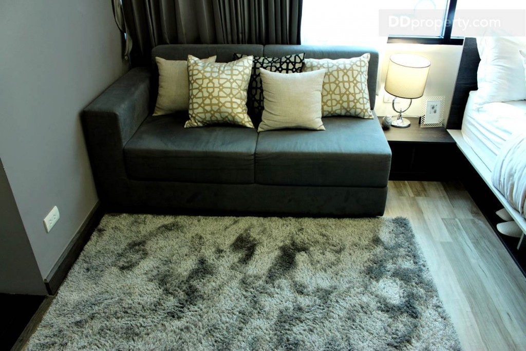 โซฟาแบบ 2 ที่นั่งตั้งอยู่ติดกับเตียงนอนมีพื้นที่สามารถนอนเล่นหรือทำกิจกรรมบนพื้นได้