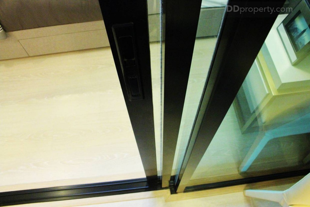ฉากกั้นห้องนอนและ Living Room เป็นกระจกใสเขียวขอบอะลูมิเนียมดำบานสไลด์แบบ 3 ตอน