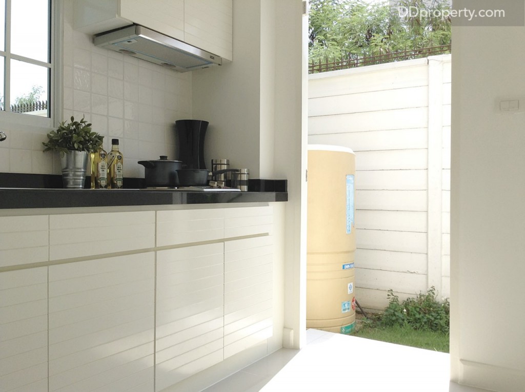 พื้นที่ครัวของบ้านจริงเป็นพื้นที่โล่ง แต่บ้านตัวอย่างตกแต่งให้เห็นว่า สามารถบิลท์อินชุดครัวติดผนังรูปตัว I ได้ยาว 3 - 4 ม. เลยทีเดียว และมีประตูเปิดออกไปยังส่วนซักล้างด้านนอกด้วย