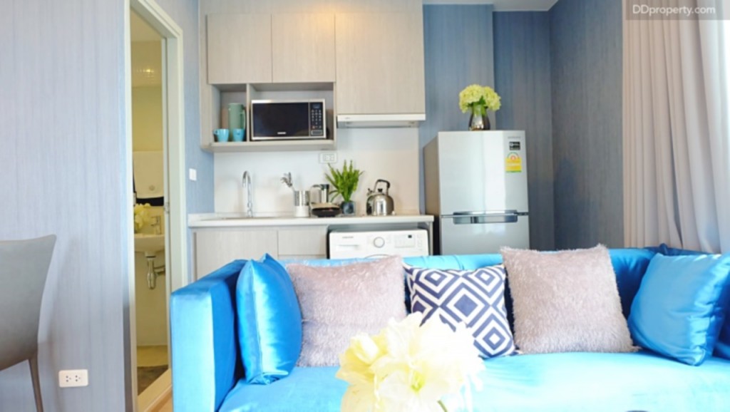 ด้านหลังโซฟา เป็นเคาน์เตอร์ครัวที่มาพร้อมกับเครื่องใช้ไฟฟ้าดังที่เห็นในภาพ หากต้องการกั้นพื้นที่ให้เป็นสัดส่วน ผู้อยู่อาศัยสามารถติดตั้ง partition กั้นส่วนระหว่างห้องนั่งเล่นกับห้องครัวได้