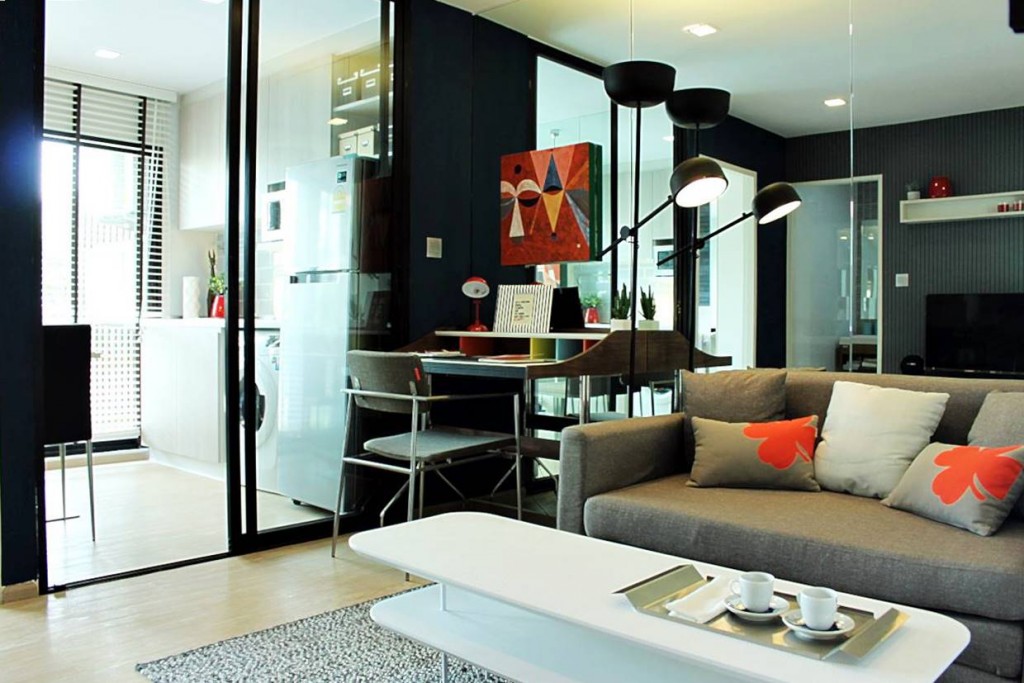 มุมมองภายในห้องนั่งเล่นของห้องตัวอย่าง ห้องตกแต่งเป็นโทนสีเข้ม แต่ดูเรียบง่ายสไตล์โมเดิร์น