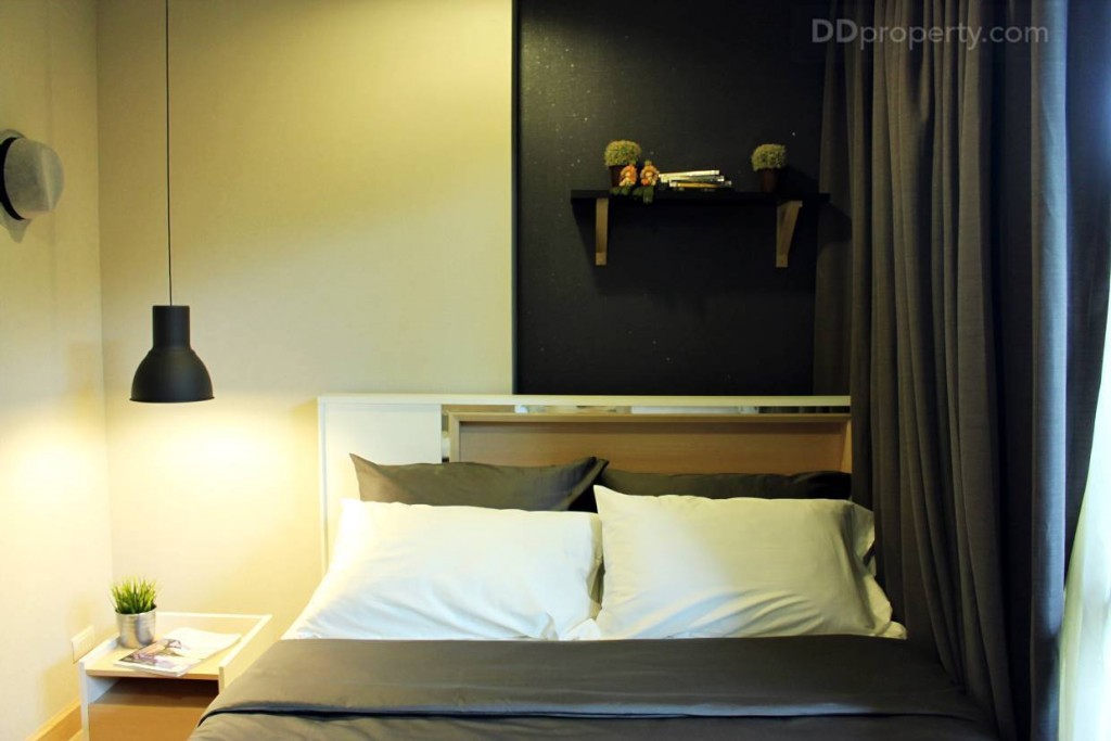 จากห้องตัวอย่างทางโครงการวางเตียงชิดหน้าต่าง เพื่อให้มีพื้นที่ว่างด้านซ้ายมือ ผนังห้องนอนเป็นสีขาบฉาบเรียบ