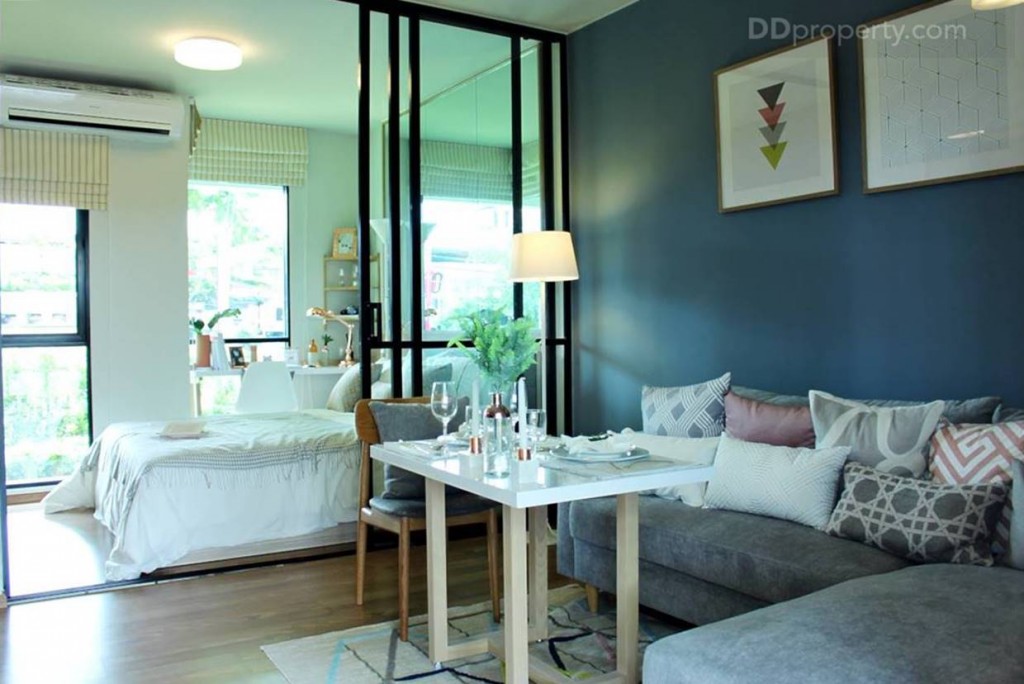 พื้นที่ด้านขวาจากทางเข้าห้องเป็นมุมห้องนั่งเล่น ผนังห้องเป็นคอนกรีตสีขาวฉาบเรียบ
