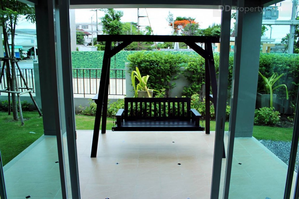 ห้องนั่งเล่นจะอยู่ติดกับเฉลียงด้านข้างบ้านซึ่งเป็นความเฉพาะตัวของบ้านแบบราชพฤกษ์ ประตูเป็นแบบบานเลื่อนกระจกใสเขียวตัดแสงขอบอะลูมิเนียมขาว