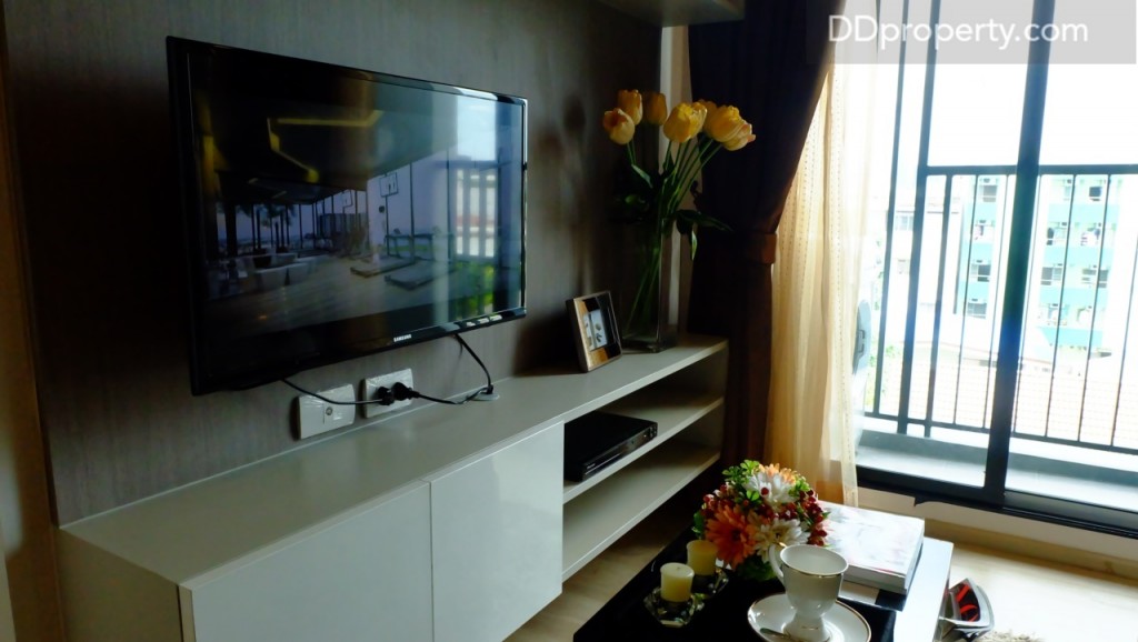 หากเลือกจัดห้องตามเลย์เอ้าท์นี้พื้นที่ตรงข้ามโซฟามีขนาดความกว้างประมาณ 2 เมตร ระยะห่างจากตัวโซฟามาถึงจุดวางทีวีประมาณ 1.5 เมตร หากต้องการให้โซนนี้ดูกว้างขึ้นอาจจะเลือกงานบิ้ลท์อินเจาะผนังเพื่อให้กลายเป็นชั้นวางชุดอุปกรณ์เครื่องเล่นต่างๆแทนที่จะเลือกบิ้ลท์อินเป็นชั้นวางยื่นออกมา