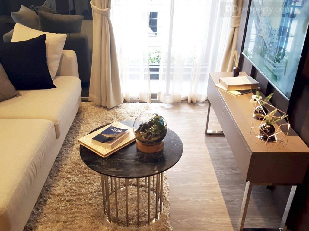 ระยะห่างจากโซฟาถึงชั้นวางทีวีอยู่ที่ประมาณ 1.5 เมตร พื้นห้องเป็นกระเบื้องยางลายไม้