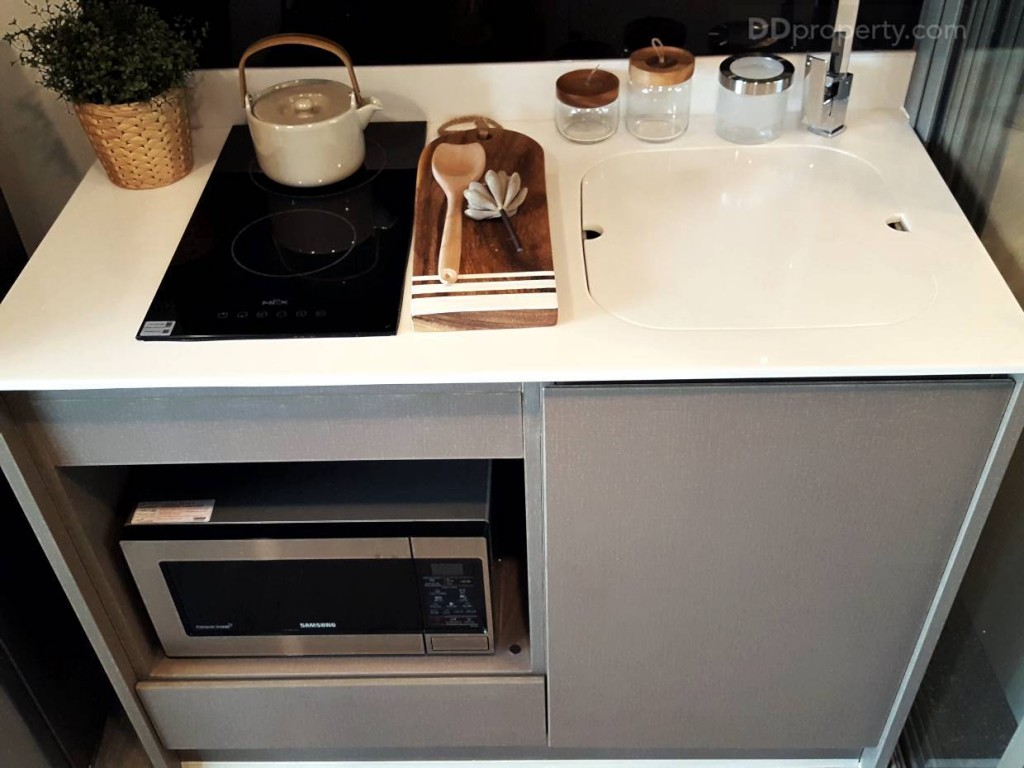 เคาน์เตอร์ครัวเป็นของ SB Furniture แบบ Soft Close มาให้ ขนาดเคาน์เตอร์ยาว 1.20 เมตร วัสดุเป็นโครงไม้ปิดผิวด้วยเมลามีน มีเตาไฟฟ้า เครื่องดูดควัน อ่างล้างจาน พร้อมฝาปิด ช่องใส่ไมโครเวฟแถมมาให้ครบ  ส่วนเคาน์เตอร์เป็นหินสังเคราะห์สีขาว มีแผ่นหินปิดตัวอ่างล้างจานมาให้ พอจะใช้อ่างล้างจานก็ยกเปิดออก อ่างล้างจานที่ให้เป็นของ Mex