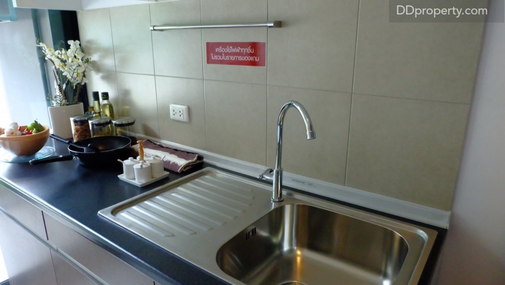 เคาน์เตอร์ครัวท็อปด้วยหินสังเคราะห์ อ่างล้างจานและก๊อกน้ำแบรนด์ Hafele, ราวแขวนผ้า (สามารถติดตะขอเพื่อแขวนถ้วยกาแฟได้) ถูกติดตั้งมาให้ตามมาตรฐานเช่นเดียวกัน ผนังครัวเป็นกระเบื้องเซรามิก 30 x 30 ซ.ม.