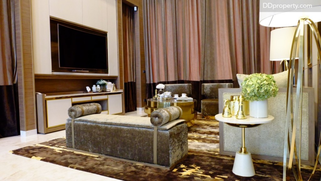 พื้นที่ห้องนั่งเล่นมีพื้นที่ประมาณ 3 x 4 เมตร สามารถจัดวางโซฟาขนาด 3 – 4 ที่นั่งได้สบาย  สำหรับครอบครัวที่มีสมาชิกเยอะ สามารถจัดวางโซฟาแชร์เพิ่มเติมได้ด้วย สำหรับบ้านเปล่าบริเวณนี้จะเป็นพื้นที่โล่งๆ ไม่มีงานบิลท์อินชั้นวางดั่งในรูปมาให้ ซึ่งบ้านตัวอย่างทำเป็นชั้นไม้แซมด้วยทองเหลืองเสริมลูกเล่นความหรูหราเข้าไปให้กับบริเวณ ตรงตำแหน่งของผ้าม่านคือหน้าต่างแนวสูงที่เมื่อเปิดออกไปจะเป็นพื้นที่หน้าบ้าน