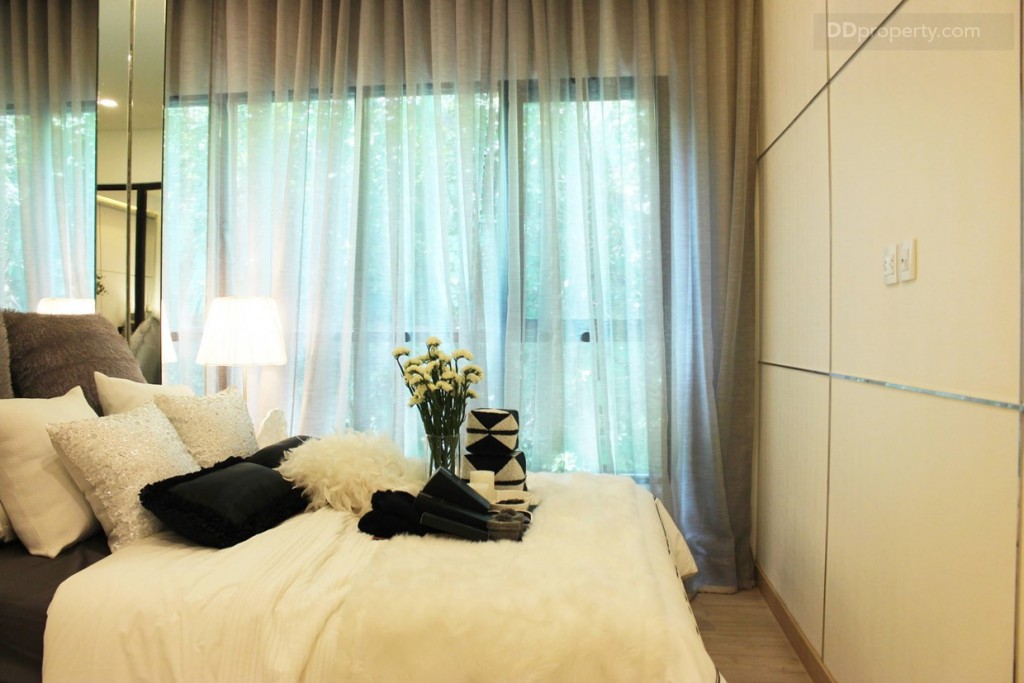 ปลายเตียงมีพื้นที่ทางเดินเล็กน้อย ผนังฝั่งตรงข้ามกับเตียงทางโครงการจะติดแอร์ ของ Daikin หรือเทียบเท่า มาให้ มีปลั๊กไฟและสายทีวี ให้ 1 ตำแหน่ง