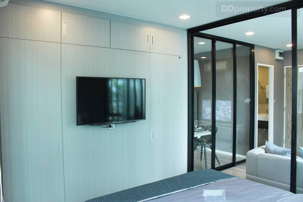 พื้นที่ปลายเตียงเป็นตู้เสื้อผ้าบิวท์อินเต็มพื้นที่ พร้อมที่เก็บของด้านบน