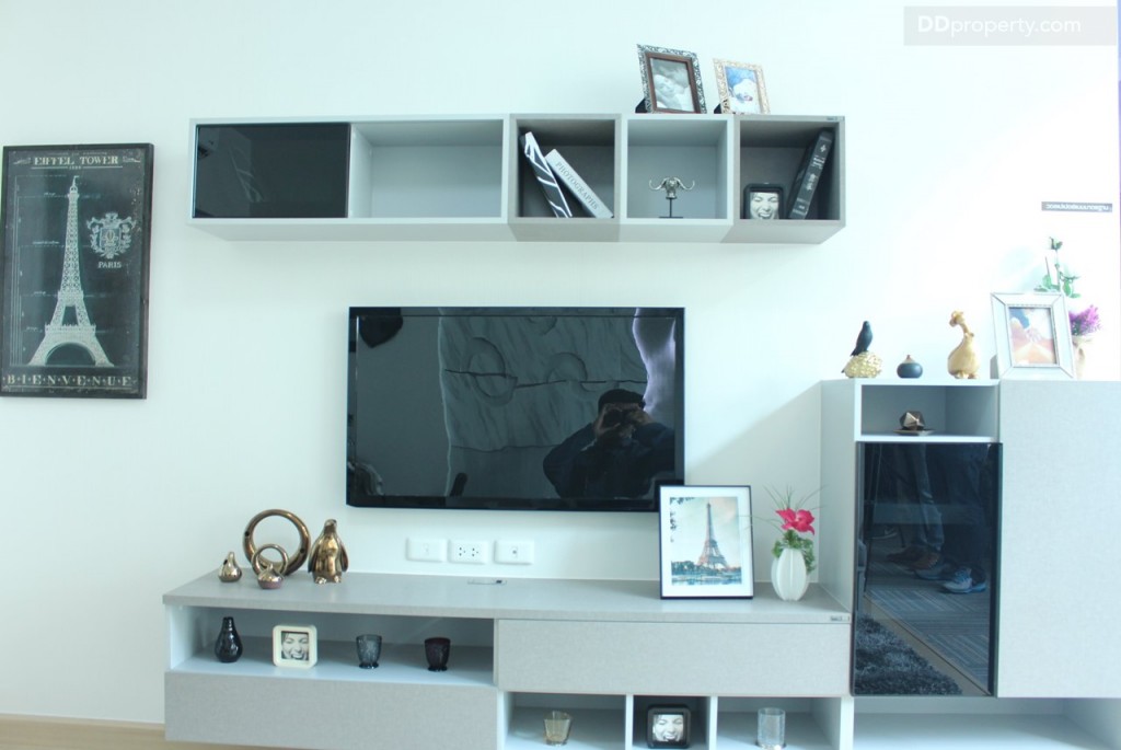 ฝั่งขาวชั้นวางทีวีถ้าเลือกแบบเอาเฟอร์นิเจอร์ก็จะได้ กล่องแขวนที่อยู่ด้านบนขนาด 180x30x30 ซม. พร้อมชั้นวางทีวีขนาด 180x40x40 ซม. และตู้รองเท้า ขนาด 80x40x100 ซม. ส่วนวัสดุปิดผิวเป็นเมลามีน เป็นสี Denim Grizzlyตัดกับ Light Grey ตามแบบที่เห็นเลย