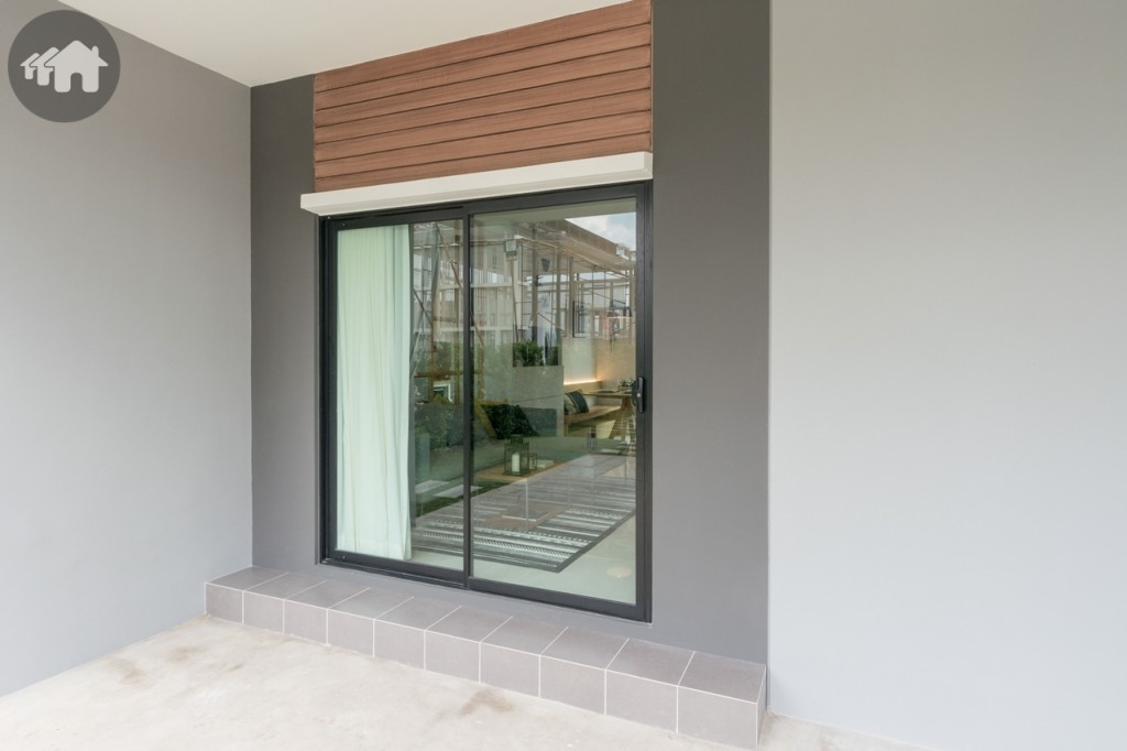 กลับมาดูหน้าบ้าน ประตูหน้าบ้านเป็นประตูกระจกบานเลื่อนแบบสลับ บานใหญ่ เพิ่มมุมมองที่กว้างขวาง โปร่งโล่ง และสบายตา