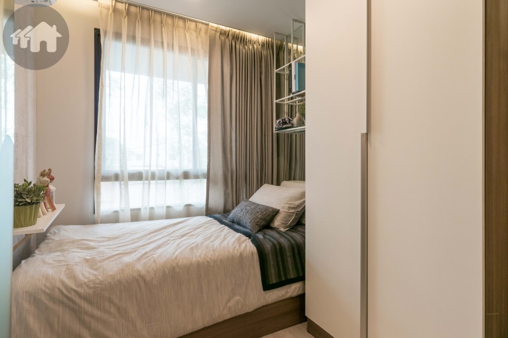 ตกแต่งเป็นห้องนอนเล็ก มาพร้อมกับฐานเตียงขนาด 3.5 ฟุต ติดกับหน้าต่างกระจกบานเลื่อนแบบสลับ ด้านข้างวางบิวท์อินตู้เสื้อผ้า ปลายเตียงตกแต่งเป็นชั้นวางของ