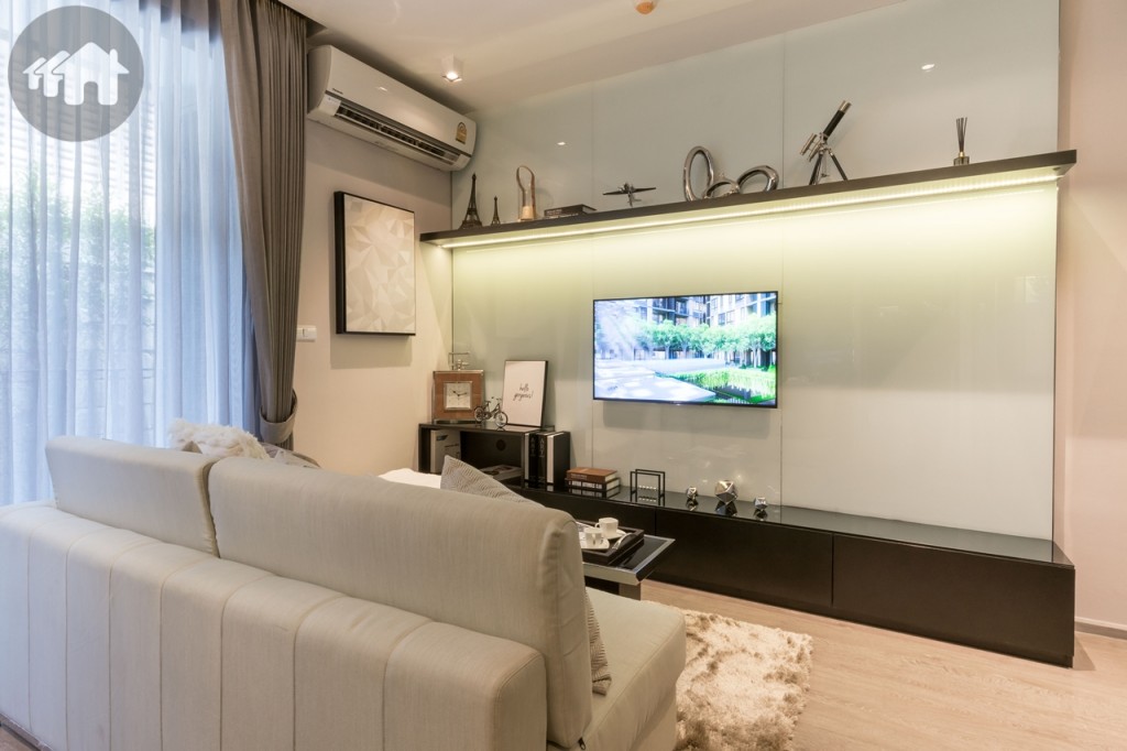 ห้องนั่งเล่นขนาดใหญ่ พร้อมชั้นวางโทรทัศน์ โต๊ะกลาง และโซฟา ชั้นวางโทรทัศน์ห่างจากโซฟาประมาณ 1.20 เมตร