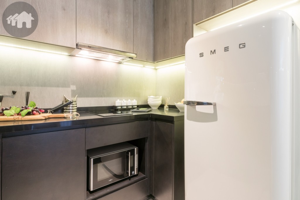 ตู้ครัวบิวท์อินบน-ล่าง พร้อมที่วางเตาไมโครเวฟ และตู้เย็น ครับครันด้วยอ่างล้างจาน เตาไฟฟ้าฐานเซรามิก 2 หัว และเครื่องดูดควันของ Teka