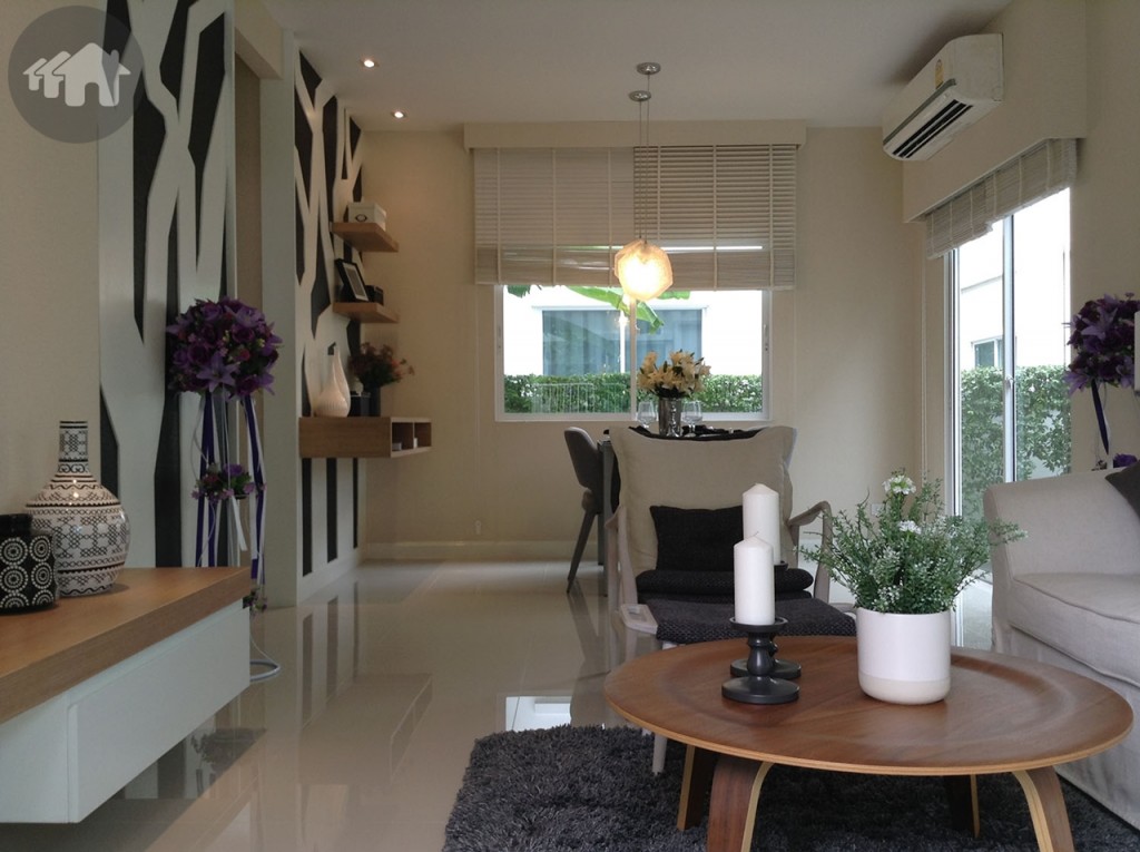 ภายในบ้านชั้นล่างนั้น บ้านมาตรฐานจะเป็นพื้นที่โล่งกว้าง แต่ในบ้านตัวอย่างออกแบบไว้เป็นไอเดียในสไตล์โมเดิร์น ให้ทุกพื้นที่เชื่อมต่อกันได้แบบเปิดโล่ง เน้นใช้เฟอร์นิเจอร์น้อยชิ้น ทั้งแบบบิลท์อินและลอยตัว โดยจัดแบ่งห้องนั่งเล่นรับแขก และโต๊ะรับประทานอาหารไว้เป็นโซนแรกของบ้าน