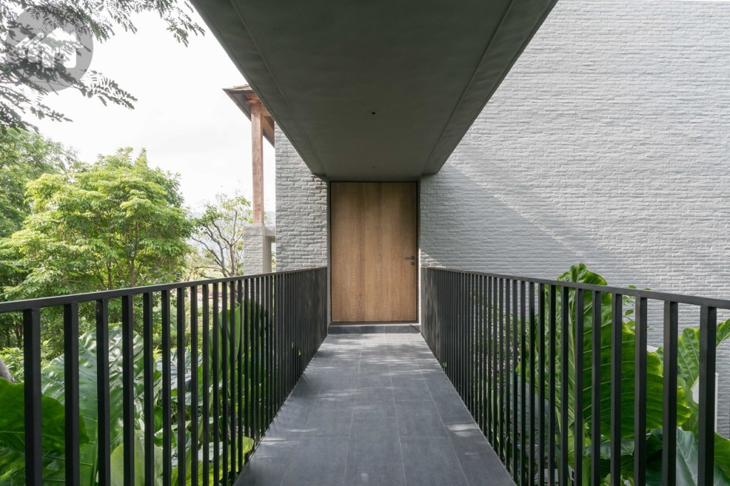 ทางเข้าบ้านอยู่บริเวณด้านหลังเชื่อมต่อกับที่จอดรถ ต้อนรับด้วยพื้นที่สีเขียวทั้ง 2 ด้าน