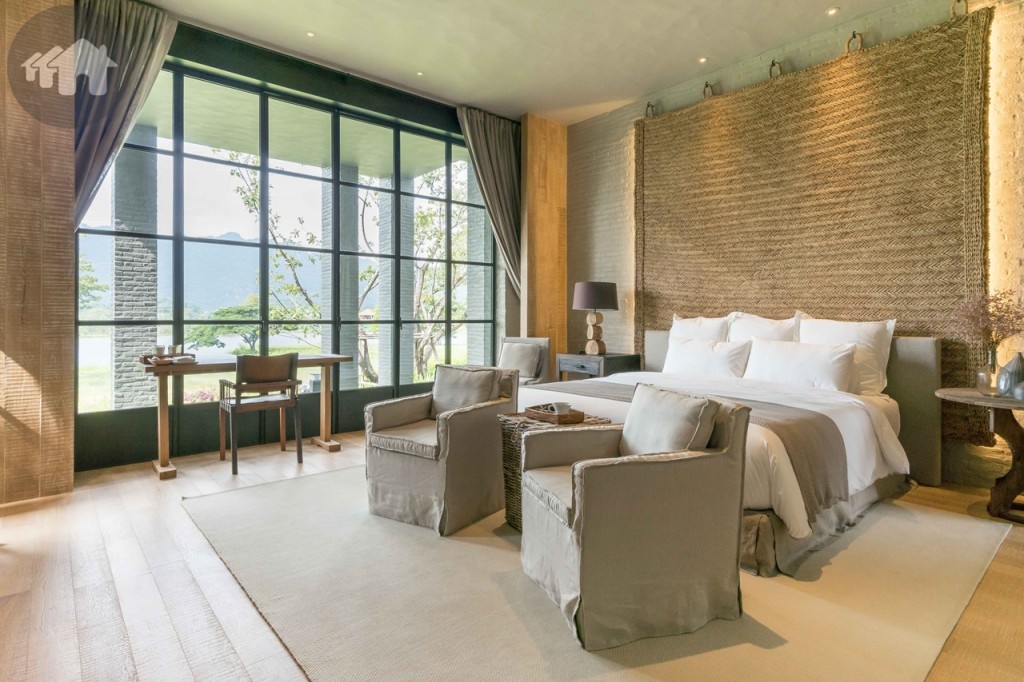 ห้องนอนชั้นล่างในโซนอาคารเดียวกับห้องนอนใหญ่ เพดานฉาบปูนให้เกิดเป็นลอนคลื่น หัวเตียงตกแต่งด้วยเชือกปอถักด้วยฝีมือช่างหัตถกรรมพื้นบ้าน