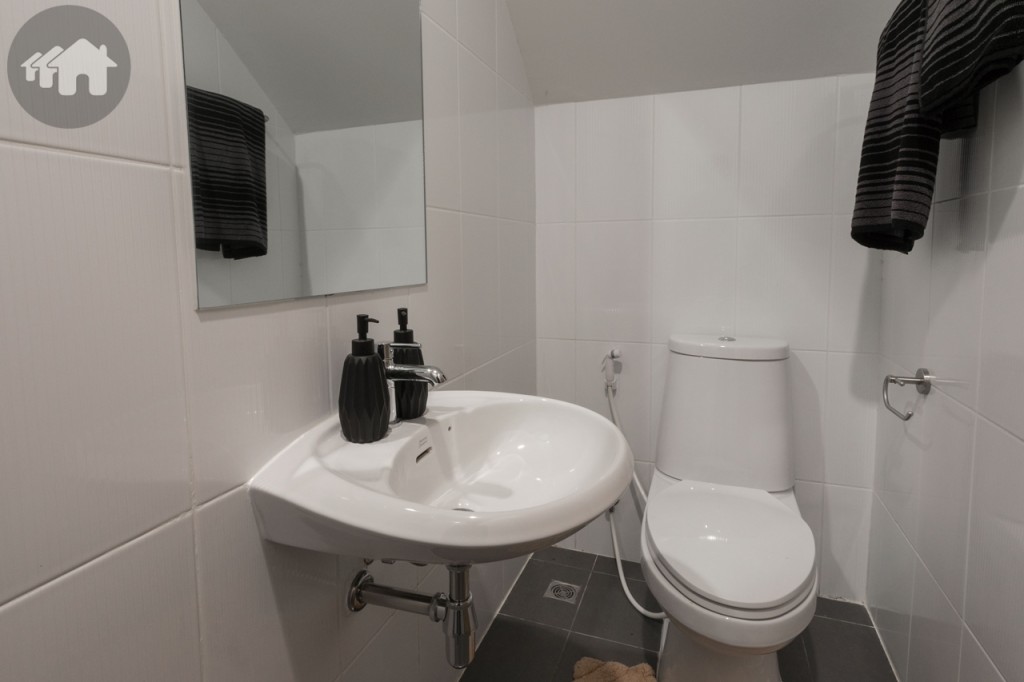 ห้องน้ำชั้นล่าง พร้อมอุปกรณ์ครบครัน พื้นปูกระเบื้องขนาด 30x30 เซนติเมตร ผนังปูกระเบื้องขนาด 25x40 เซนติเมตรสุขภัณฑ์ในห้องน้ำจะไม่ได้ใช้ยี่ห้อเดียวกันทั้งหลัง แต่จะเลือกยี่ห้อที่มีดีไซน์เหมาะสมกับแต่ละห้อง มีทั้ง American Standard, Nahm และ Karat