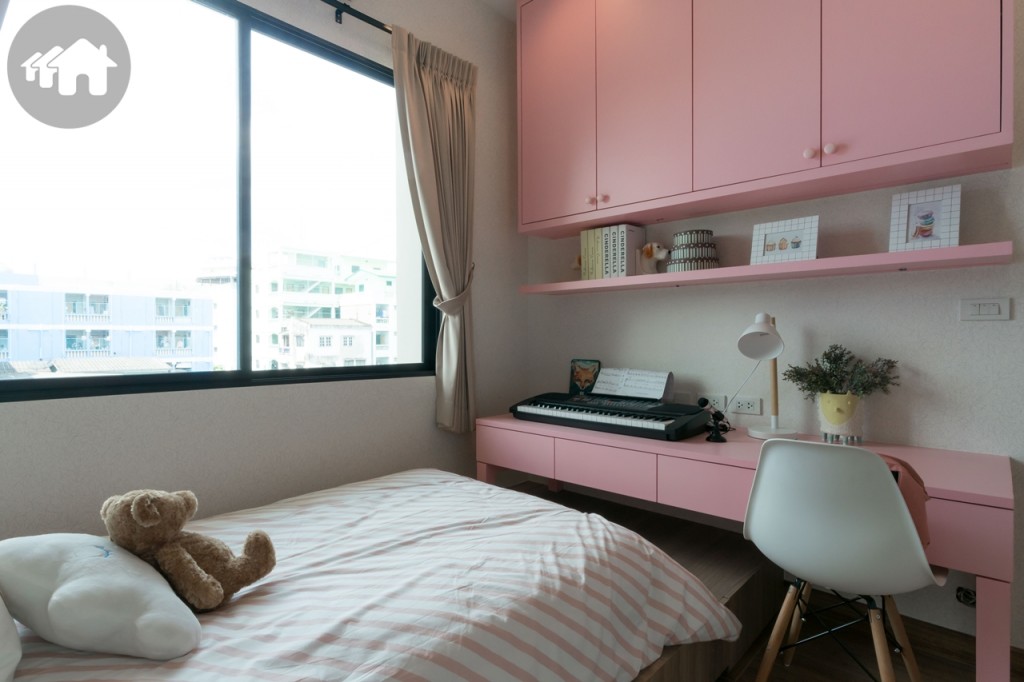 ปลายเตียงตกแต่งเป็นโต๊ะเขียนหนังสือ และชั้นวางของ หน้าต่างกระจกบานเลื่อนแบบสลับบานใหญ่ รับแสงธรรมชาติ