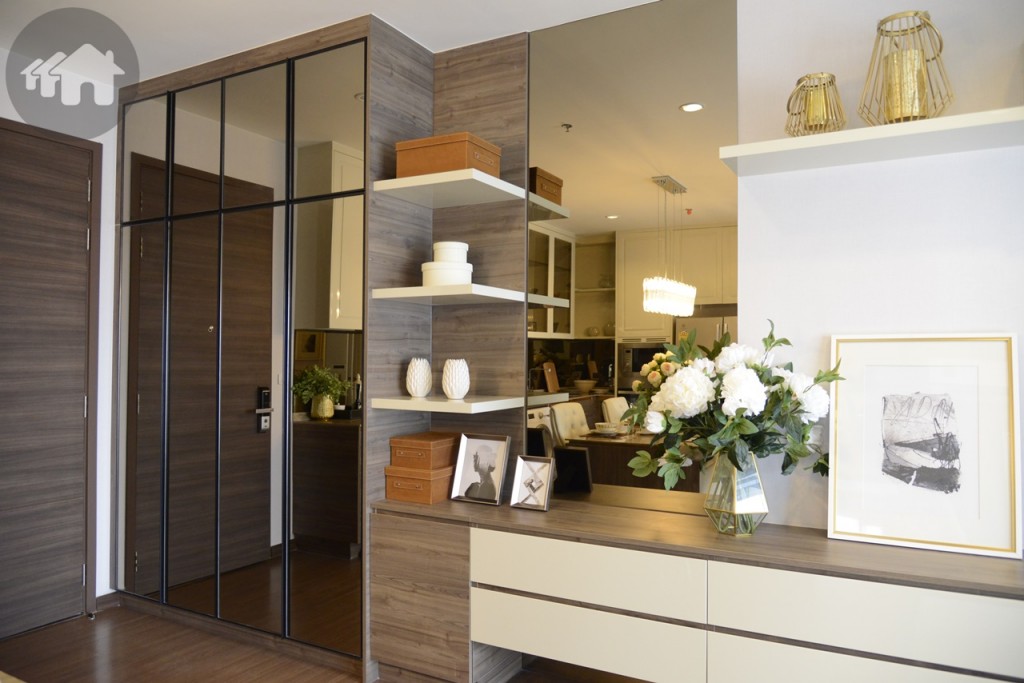 ส่วนด้านริมประตูจะมีตู้เก็บรองเท้า  ชั้นวางของสำหรับตั้งโชว์ และโต๊ะติดแบบ Built-in พร้อมลิ้นชัก นอกจากนี้ยังติดกระจกสีทองตรงผนัง ช่วยทำให้ห้องดูกว้างและสว่างมากขึ้น