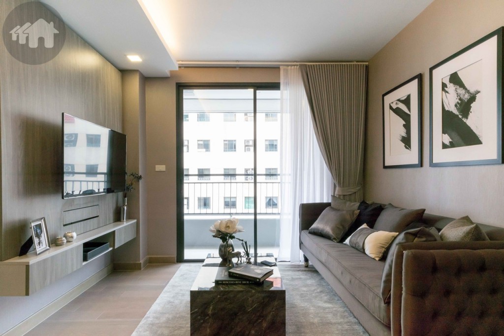The living room is exquisitely outfitted with a long sofa, a coffee table, a shelf and a TV (from Samsung), a curtain (light fabrics) and a PVC drape (heavier fabrics). The distance between the sofa and TV is approximately 1.90 metres