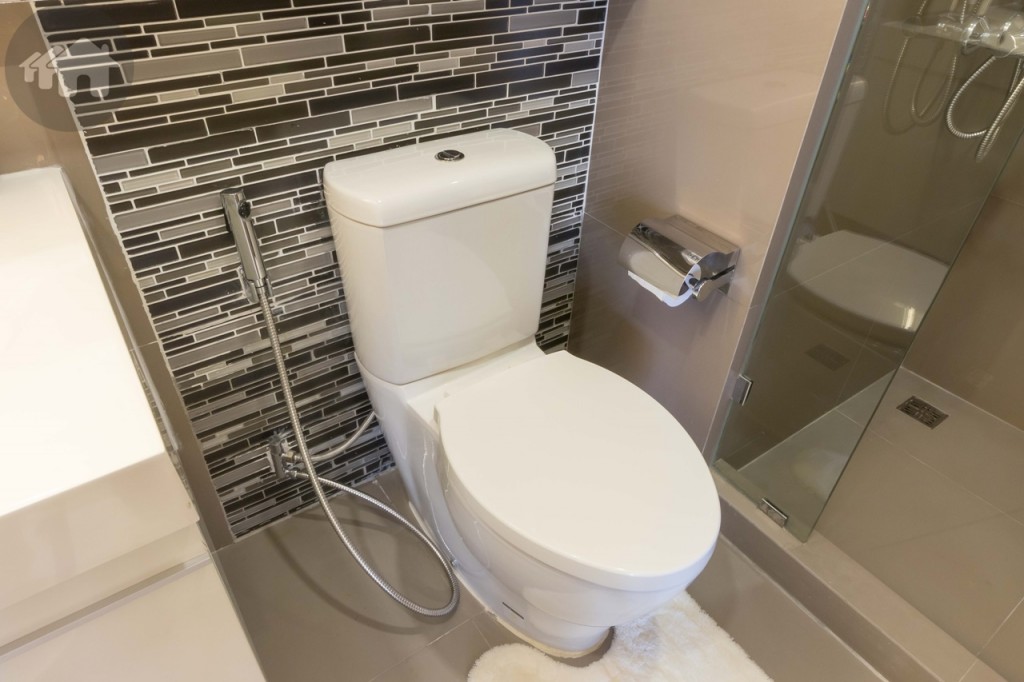 The toilet is also from Kohler, accompanied by a bidet shower and a toilet paper holder