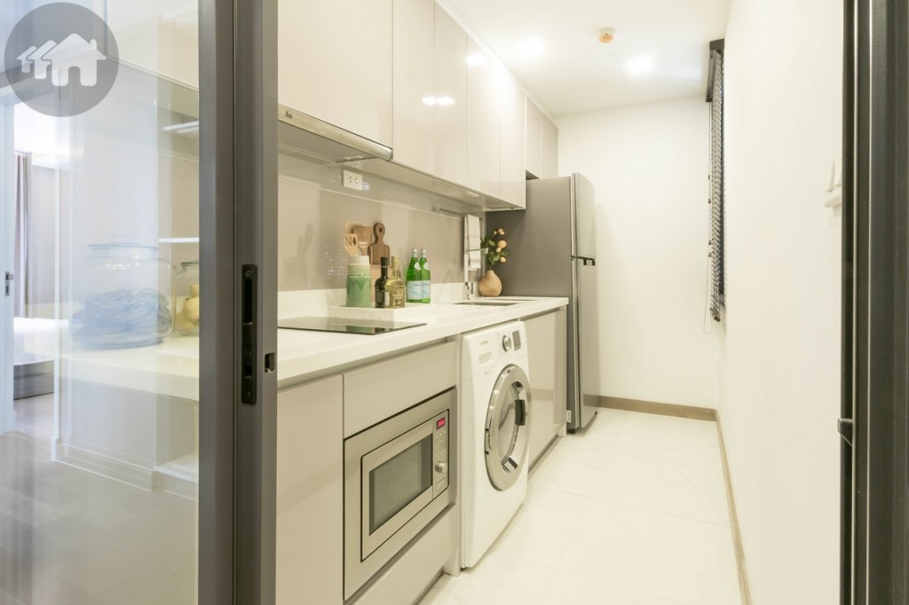The kitchen is enclosed within a sliding door and includes high-gloss upper and lower cabinets, artificial stone countertop, backsplash; sink, hobs, hood, and microwave are from Teka. The walkway is around 90 cm. wide and laid with 60x60 cm. tiles