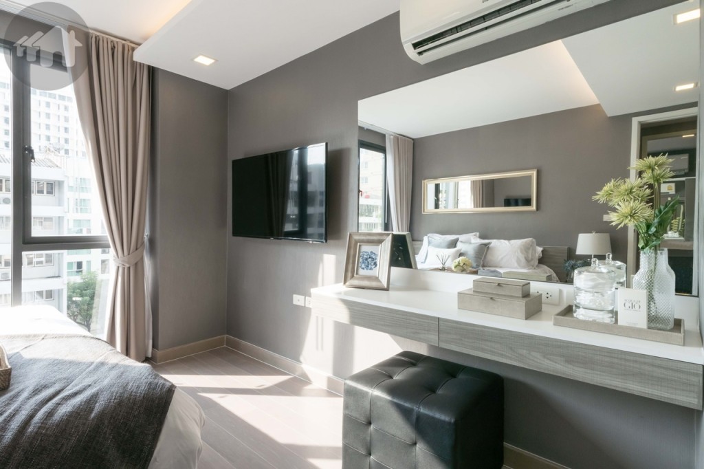 An extensive dressing table and mirror at the end of bed, next to a wall-mounted TV that is 1.25 metres from the bed
