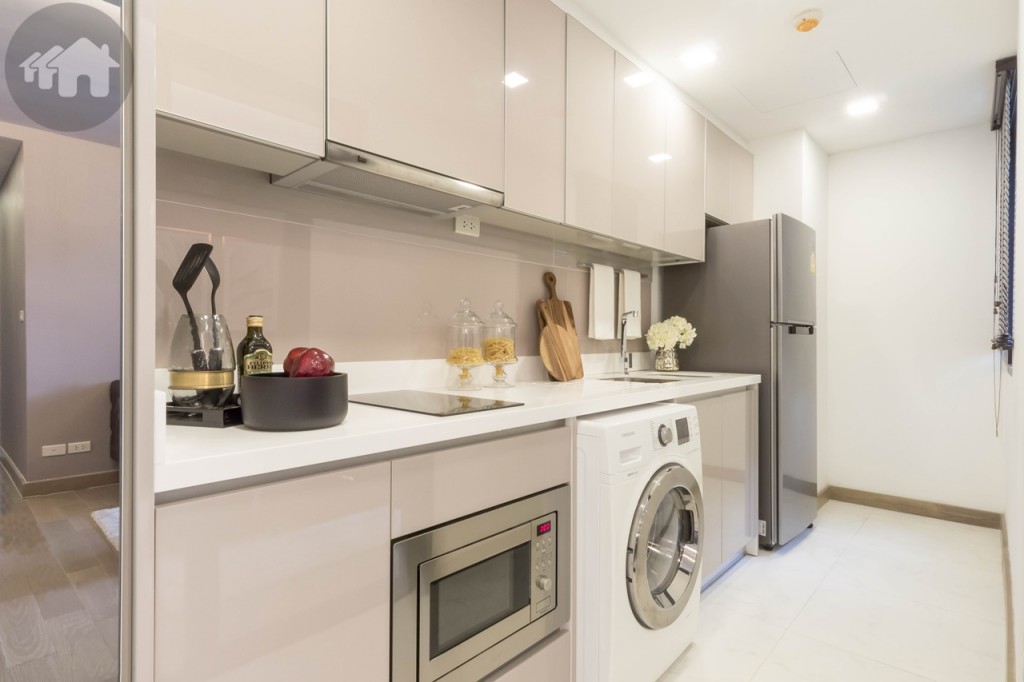 Kitchen is floored with 60x60 tiles (walkway 90 cm. wide) and consists of high-gloss upper and lower cabinets, artificial-stone countertop, backsplash, Teka-branded sink, hobs, hood, and microwave, and a refrigerator from Samsung. There’s a window blind opposite the fridge