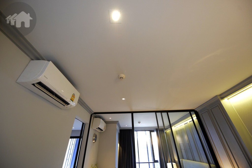 เมื่อเปิดเข้ามาในห้อง จะเจอมุมนั่งเล่นก่อน มองภาพรวมเป็นห้องหน้ากว้าง ความสูงระหว่างเพดานกับพื้น 2.4 เมตร ดูโปร่งโล่ง พร้อมติดตั้งไฟแบบดาวน์ไลท์