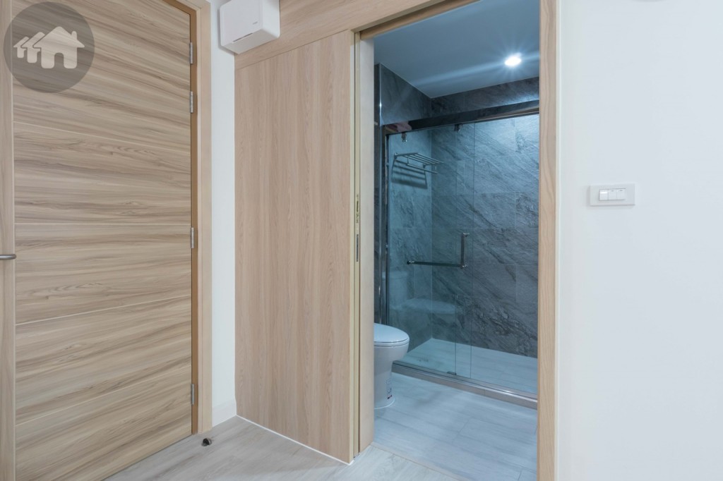 ใกล้กับห้องรับแขกเป็นห้องน้ำกั้นด้วยประตูไม้อัดปิดแผ่นลามิเนต ออกแบบพิเศษเป็นรางเลื่อนด้านบนไม่ต้องกลัวเดินสะดุด และเพิ่มพื้นที่มากขึ้นกว่าประตูแบบบานสวิง