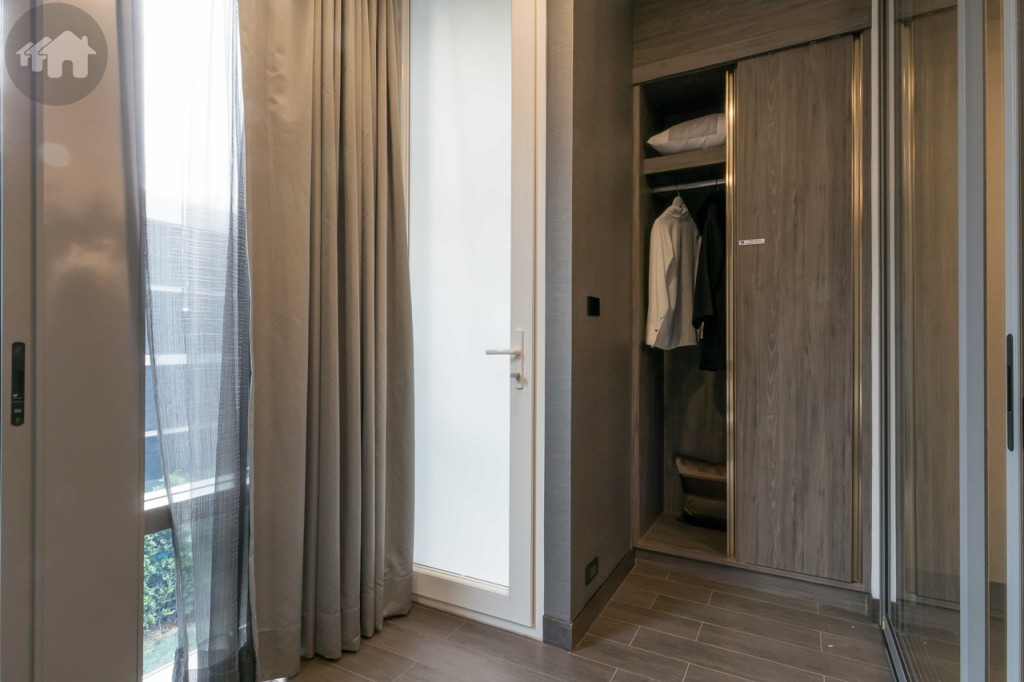 ปลายเตียงเป็นตู้เสื้อผ้าบิลท์อิน และประตูเชื่อมต่อกับระเบียงติดตั้งคอมเพรสเซอร์เครื่องปรับอากาศ และเครื่องซักผ้า