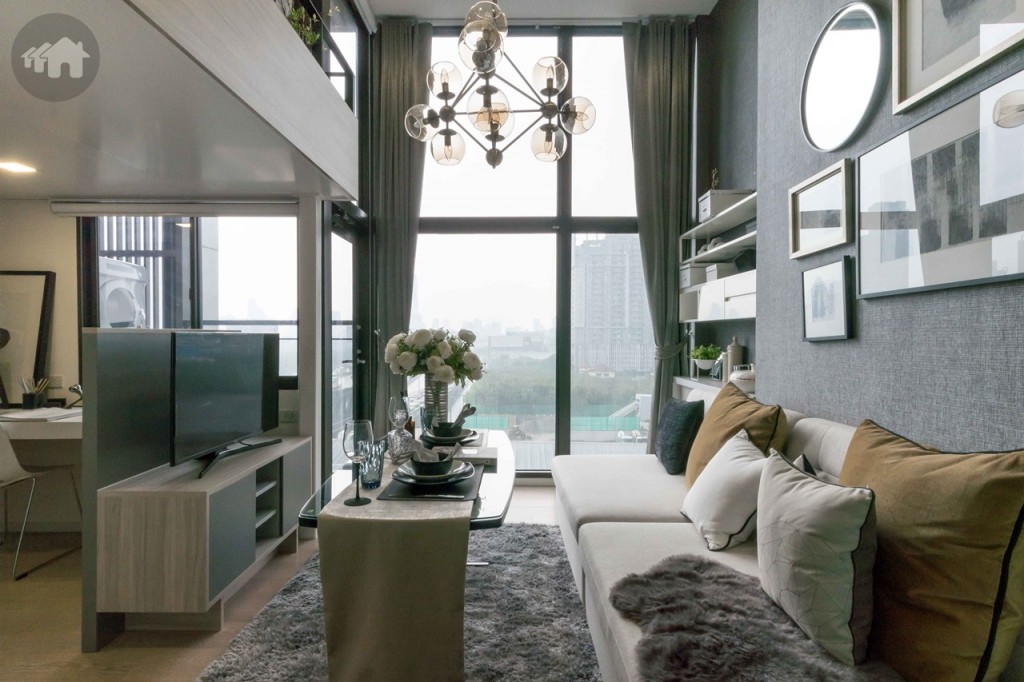 ห้องนั่งเล่นกว้างขวาง พื้นปูลามิเนตหนา 8 มิลลิเมตร เปิดรับวิวด้วยกระจกบานใหญ่สูงจรดเพดาน ติดตั้งผ้าม่านคู่ 1 ชุด ตู้วางโทรทัศน์ห่างจากโซฟาประมาณ 1.30 เมตร 