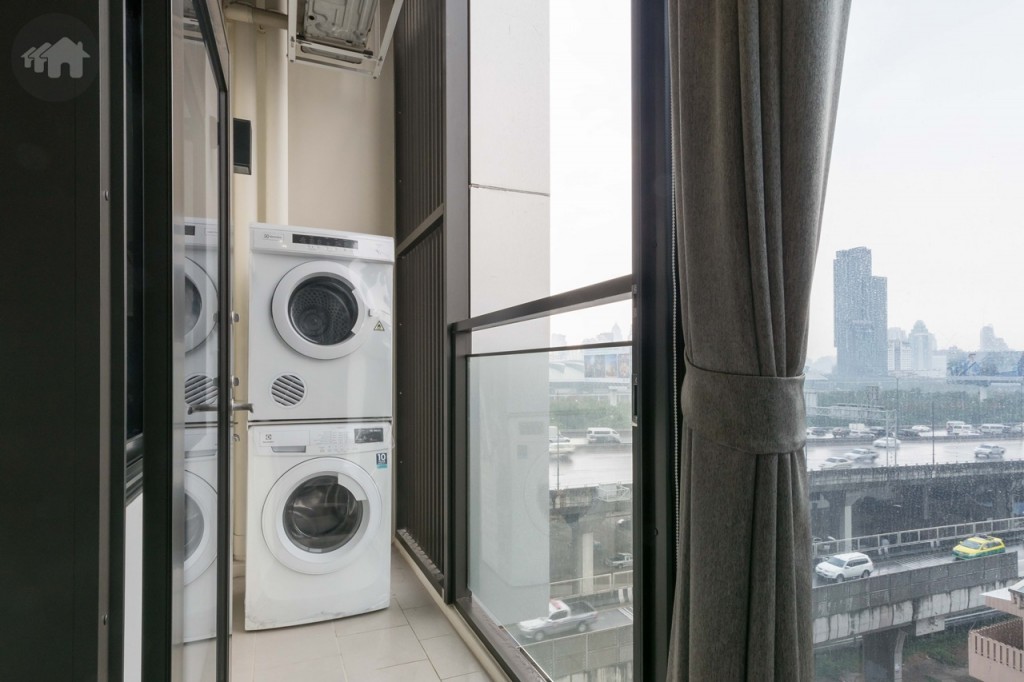 ระเบียงกั้นเป็นสัดส่วนด้วยประตูกระจกบานสวิง ขอบประตูยกสูงประมาณ 10 เซนติเมตร ระเบียงกว้างประมาณ 1 เมตร ยาวประมาณ 2.50 เมตร รั้วสูงประมาณ 1.30 เมตร พื้นปูกระเบื้องเซรามิกขนาด 30x30 เซนติเมตร มาพร้อมเครื่องซักผ้า และเครื่องอบผ้าของ Electrolux ติดตั้งก๊อกน้ำและท่อระบายน้ำให้เรียบร้อย ด้านบนติดตั้งคอมเพรสเซอร์เครื่องปรับอากาศ พร้อมระแนงกั้นเพื่อความสวยงาม