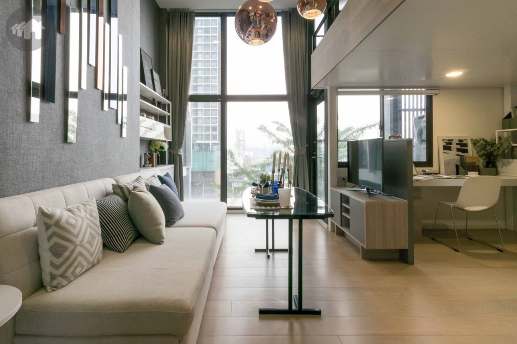 ห้องนั่งเล่นกว้างขวาง เปิดรับวิวด้วยกระจกบานใหญ่สูงจรดเพดาน ตู้วางโทรทัศน์ห่างจากโซฟาประมาณ 1.40 เมตร 