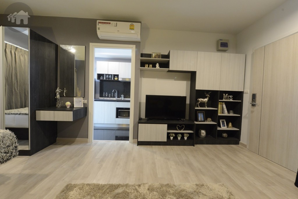 ชิดผนังมีการติดตั้งชั้นวางของบิลท์อินให้ และที่วางทีวี ถัดไปเป็นประตูไปส่วนห้องครัว