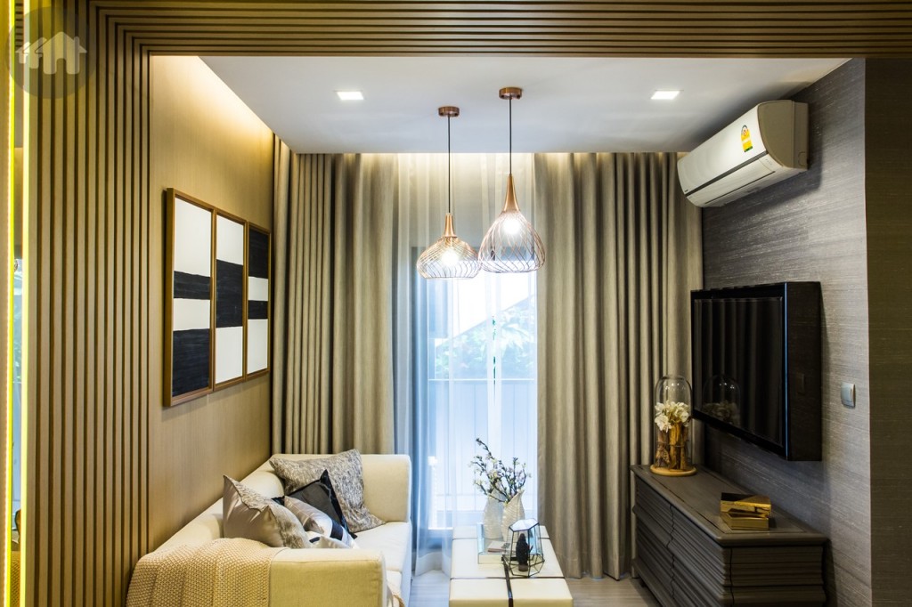 ถัดจากห้องครัวจะเป็นบริเวณสำหรับนั่งพักผ่อน แม้จะไม่ได้มีที่กั้นแต่ก็แยกเป็นสัดส่วนได้อย่างลงตัว มีโต๊ะกาแฟไว้สำหรับวางของ ทีวีแบบติดผนัง 