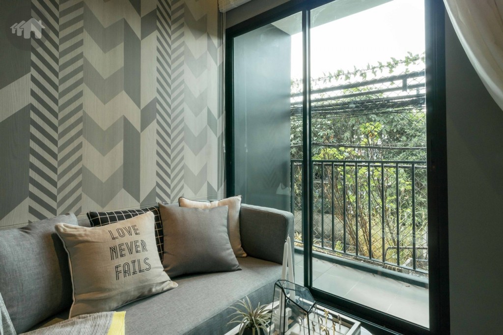 ห้องนั่งเล่นเชื่อมต่อกับระเบียงด้วยประตูกระจกบานเลื่อนแบบ 2 ตอน บานใหญ่ ขอบประตูสูงประมาณ 10 เซนติเมตร 