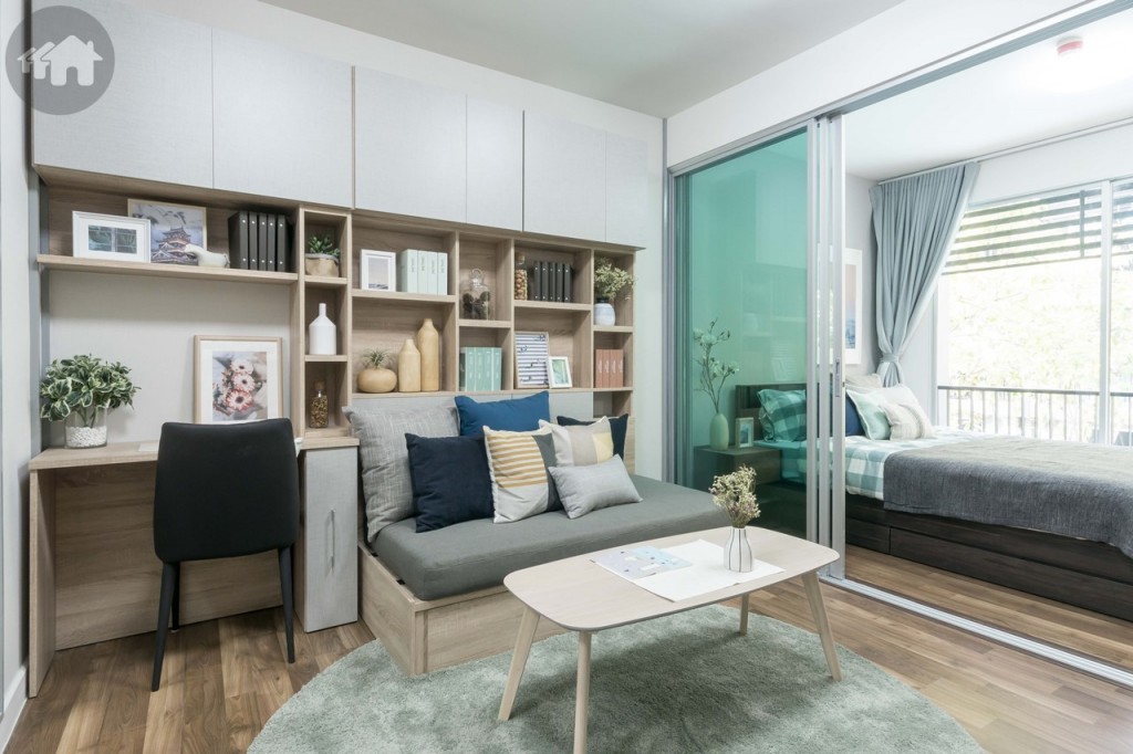 ตรงข้ามเป็นโซนโซฟา ด้านข้างตกแต่งเป็นโต๊ะเขียนหนังสือ ด้านบนเป็นชั้นวางของตกแต่งห้อง