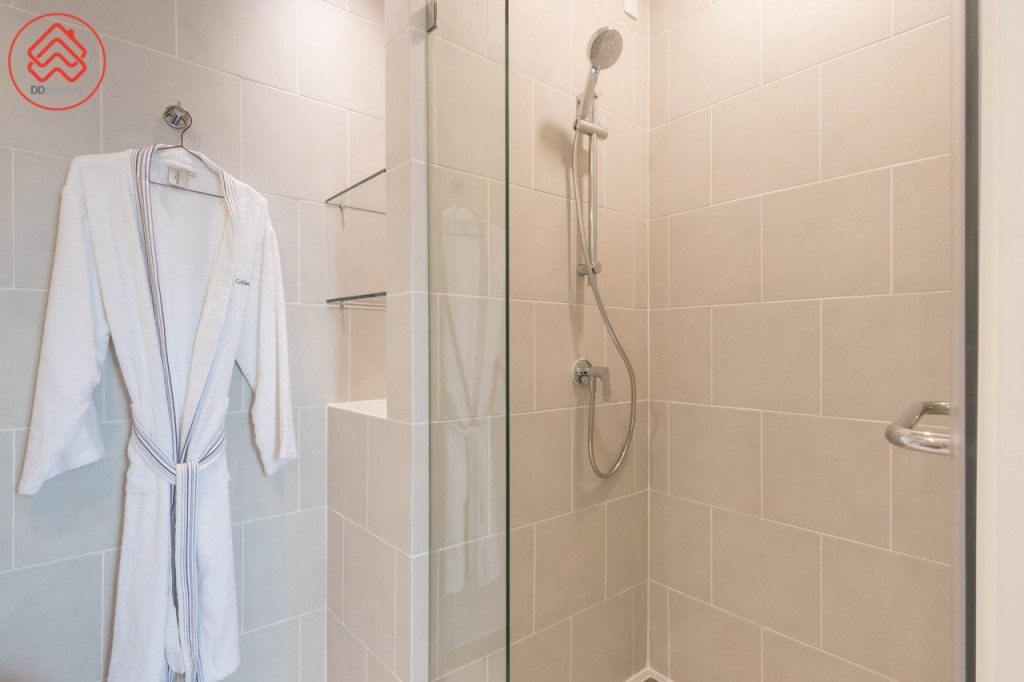 พื้นที่อาบน้ำกั้นเป็นสัดส่วนด้วยบานกระจกนิรภัย ขอบประตูยกสูงประมาณ 5 เซนติเมตร พื้นที่อาบน้ำกว้างประมาณ 80 เซนติเมตร ยาวประมาณ 95 เซนติเมตร มาพร้อมฝักบัวของ Hafele ด้านข้างมีที่วางอุปกรณ์อาบน้ำ ด้านหน้าเจาะเป็นช่องสำหรับวางเครื่องใช้ในห้องน้ำ