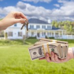 Handing Over Cash For House Keys in Front of Beautiful New Home.